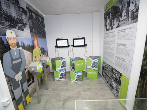 Bergisches Grauwackemuseum Ein Ausstellungsraum mit Infografiken, Würfeln und interaktiven Bildschirmen vor großer Wandinstallation.