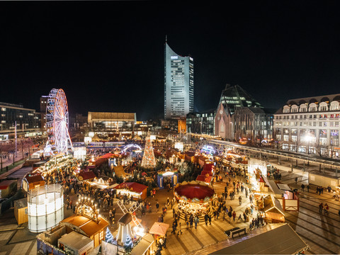 Blick auf den hell erleuchteten Augustusplatz mit dem Märchenwald und Riesenrad am Abend mit dem Gewandhaus und City-Hochhaus im Hintergrund