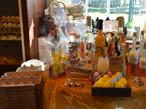 Hielscher Hof Ein Tisch mit regionalen Produkten, darunter Weinflaschen, Eier, Liköre und handgefertigte Dekorationen.