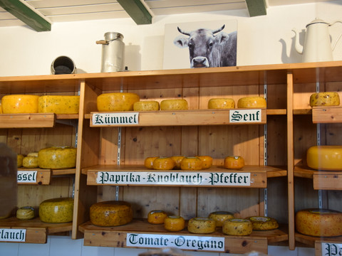 Thomashof Burscheid  Käsesorten auf Holzregalen in einem ländlichen Laden, dekoriert mit einer Tierabbildung.