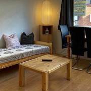 wohnzimmer_holighaus.jpg Wohnraum mit Holzmöbeln und zum Sofa umfunktionierten BettLiving room with wooden furniture and bed converted into a sofa