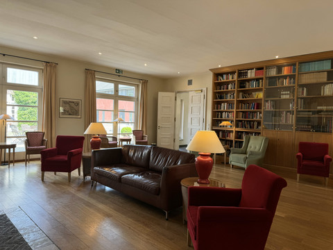 Malteser Kommende - Innenansicht Gemütlicher, heller Leseraum mit roten Sesseln, einem Ledersofa und gut gefüllten Bücherregalen im Hintergrund.