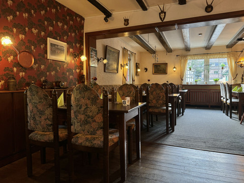 Landhaus Orbach Innenansicht Gemütliches Restaurant mit rustikaler Einrichtung, blumengemusterten Stühlen und gedämpftem Licht.
