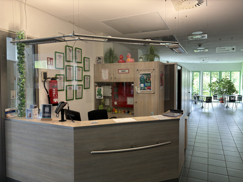 Hallenbad Badino Kassenbereich Rezeption in einem modernen Gebäude mit Pflanzen und Sitzbereich im Hintergrund.