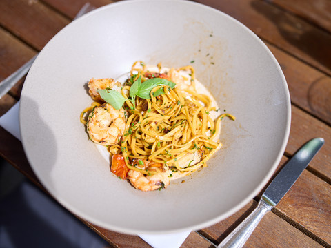 Biergarten Altenberger Hof <p>Ein Teller mit Spaghetti und Meeresfrüchten, dekoriert mit frischen Kräutern auf einem Holztisch.</p>