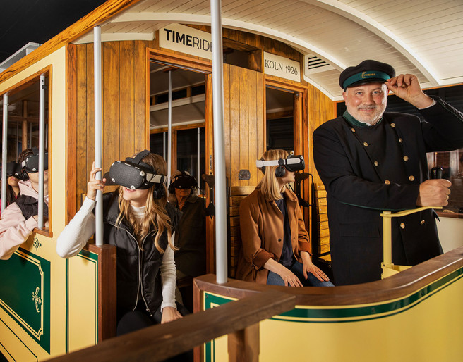Timeride SENSEUM Personen in einer historischen Straßenbahn tragen VR-Brillen und erleben eine virtuelle Zeitreise.People in a historic streetcar wear VR glasses and experience a virtual journey through time.