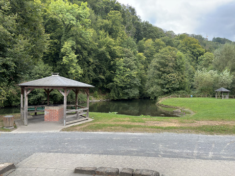 Aggerstrand in Ründeroth Holzpavillon an einem kleinen Teich, umgeben von grünen Bäumen in einer ruhigen Waldlandschaft.
