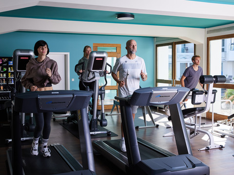 Fitnesstraining Menschen trainieren in einem modernen Fitnessstudio auf Laufbändern und einem Fahrradtrainer.