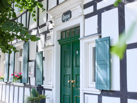 Restaurant Zur Post Ein traditionelles Fachwerkhaus mit grünem Eingang und blühenden Fensterkästen an sonnigem Tag.