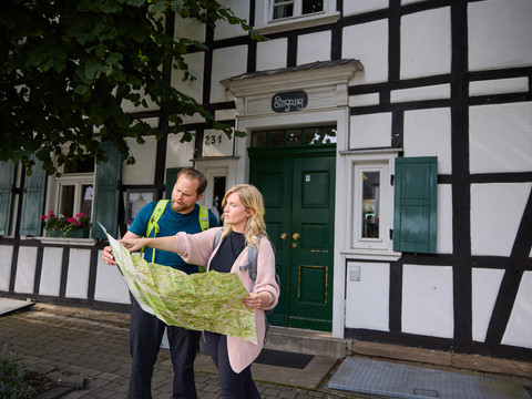 Restaurant Zur Post <p>Ein Paar steht vor einem Fachwerkhaus in Kürten und betrachtet eine Wanderkarte.</p>