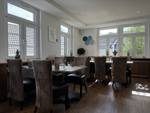 Innenansicht Gemütliches Restaurant mit eleganter Einrichtung, großen Fenstern und gedeckten Tischen für Gäste.