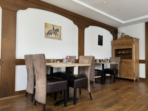 Innenansicht Ein gemütliches Restaurant mit Holzmöbeln, braunen Stühlen und Dekoration an weißen Wänden.
