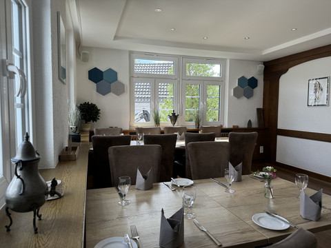 Innenansicht Helles, gemütliches Restaurant mit Holzinterieur, gedeckten Tischen, großen Fenstern und Wanddeko.