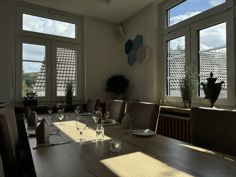 Innenansicht Ein stilvoll gedeckter Tisch in einem eleganten Raum mit großen Fenstern und gemütlichem Ambiente.