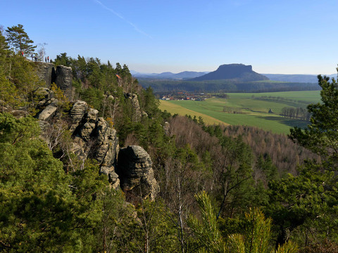 Felsiger Aufstieg mit Metalltreppe in einer bergigen Landschaft, Bäume und Himmel.