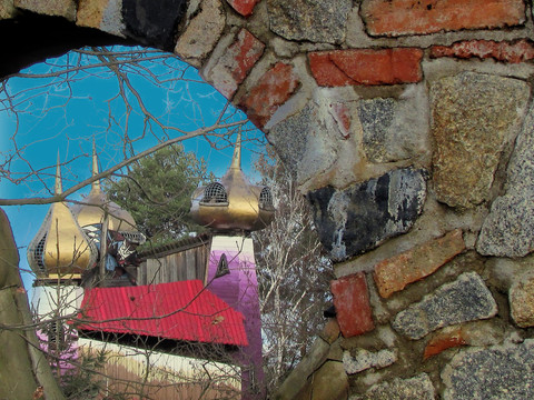Auf den Spuren Turisedes Durch ein Steinfenster sichtbar: Phantasievolle Kuppeln und bunte Holzdächer im Hintergrund.Visible through a stone window: fanciful domes and colorful wooden roofs in the background.Viditelný kamenným oknem: v pozadí fantaskní kopule a barevné dřevěné střechy.Widoczne przez kamienne okno: fantazyjne kopuły i kolorowe drewniane dachy w tle.Zichtbaar door een stenen raam: prachtige koepels en kleurrijke houten daken op de achtergrond.Visibile attraverso una finestra in pietra: cupole fantasiose e tetti in legno colorati sullo sfondo.