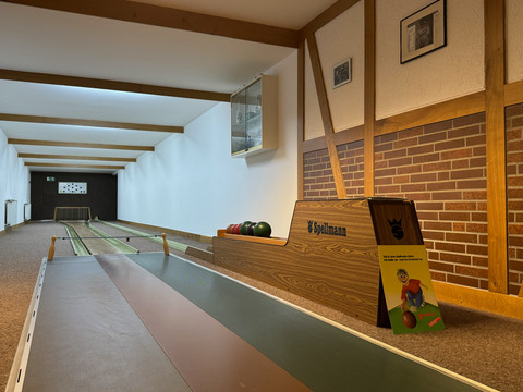 Landhaus Fuchs - Kegelbahn Kegelbahn mit brauner Holzverkleidung, Kegeln und Ballhaltern an der Wand, im hell erleuchteten Raum.