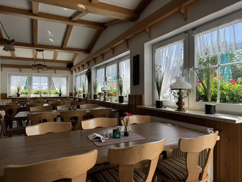 Landhaus Fuchs - Ansicht Innnenbereich Ein gemütlicher Gastraum mit rustikalen Holzmöbeln, blühenden Fensterkästen und einladendem Ambiente.