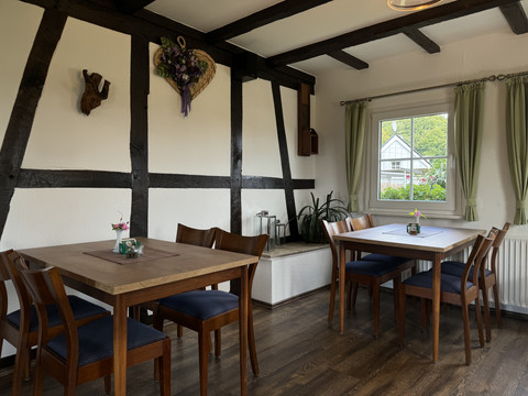 Landhaus Fuchs - Ansicht Innenbereich Gemütlicher Essbereich in rustikalem Stil, Holzdeckenbalken, Fenster mit Blick nach draußen.