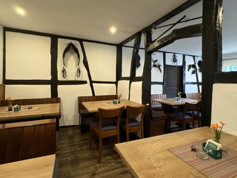 Landhaus Fuchs - Ansicht Innenbereich Gemütliche Gaststube mit rustikalen Holzbänken, dunklen Holzbalken und dezenten Dekorationen.