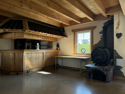 Jägerhof - Veranstaltungsraum Gemütliche Holzhütte mit rustikaler Bar, Ofen und Tageslichtfenster, vermittelt eine einladende Atmosphäre.