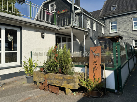 Jägerhof - Ansicht Innenhof Eingangsbereich eines traditionellen Fachwerkhauses mit Blumen und "Willkommen"-Schild aus Holz.
