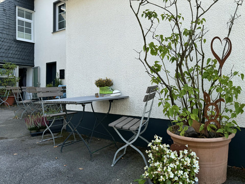 Jägerhof - Innenhof Ein einladender Außenbereich mit Holzbänken und Tischen, umgeben von Pflanzen und Blumentöpfen.