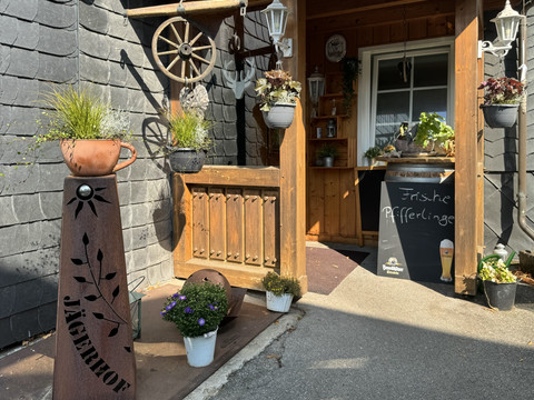 Jägerhof - Ansicht Tür Innenhof Eingang eines rustikalen Restaurants mit Blumen und Tafeln, die "Frische Pfifferlinge" bewerben.