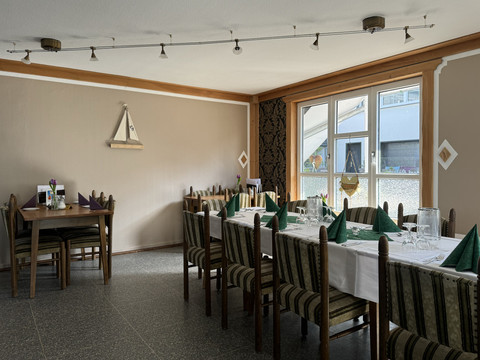 Jägerhof - Innenbereich Ein gemütlich gedecktes Esszimmer mit zwei langen Tischen, Stühlen und dekorativen Tischaccessoires.