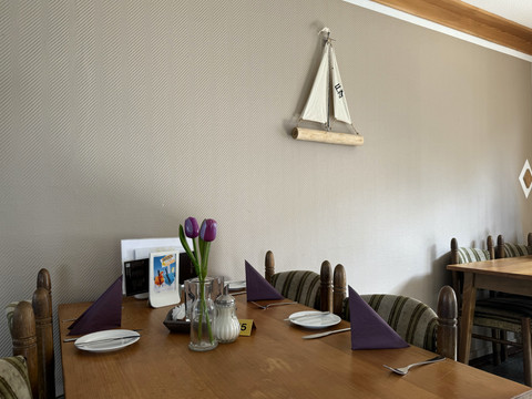 Jägerhof - Innenbereich Ein gemütlicher Tisch in einem Restaurant, gedeckt mit lilafarbenen Servietten und Dekoration.