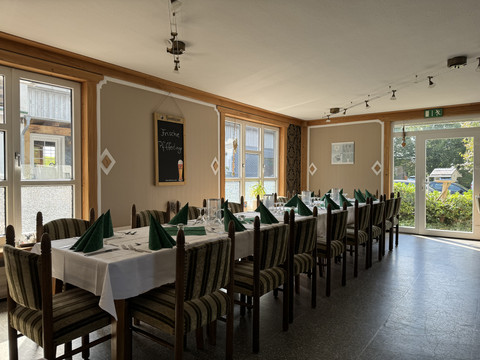 Jägerhof - Innenbereich Ein gemütlich eingerichteter Speiseraum mit gedeckten Tischen und grünen Servietten, Blick nach draußen.