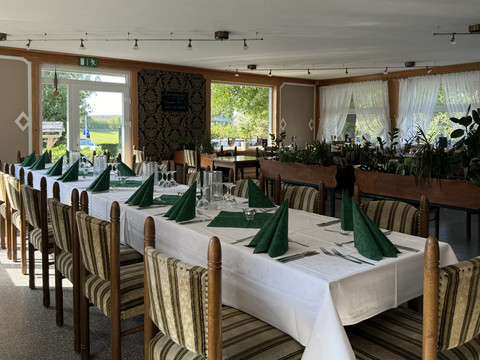 Jägerhof - Innenbereich Ein festlich gedeckter Tisch in einem hellen, gemütlichen Restaurant mit grünen Servietten.