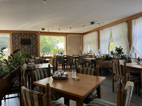 Jägerhof - Innenbereich Gemütliches, lichtdurchflutetes Restaurant mit Holzmöbeln, eleganter Dekoration und großen Fenstern.