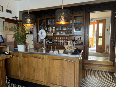 Jägerhof - Bar Gaststube mit Holztresen und Zapfhähnen, dekorativen Lampen und Regalen mit Flaschen im Hintergrund.