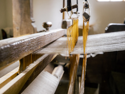 LVR-Freilichtmuseum Lindlar Altes, hölzernes Webstuhlgestell mit gespannten Fäden in einer traditionellen Textilwerkstatt.
