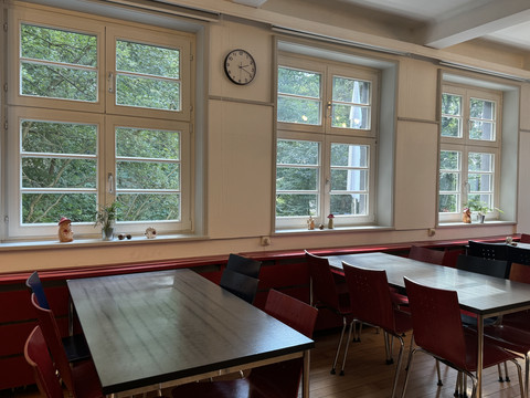 Jugendherberge Radevormwald - Speisesaal <p>Ein heller Raum mit roten Stühlen, Tischen und großen Fenstern, die auf grüne Bäume blicken.</p>