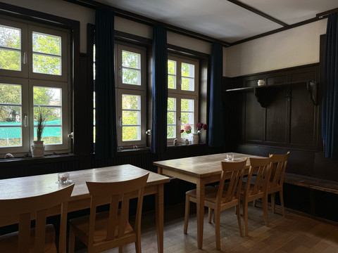 Jugendherberge Radevormwald  Zwei Holztische mit Stühlen in einem gemütlichen Raum mit großen Fenstern und Blumendekorationen.