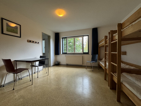 Jugendherberge Radevormwald - Ansicht Viererzimmer Eine einfache Jugendherbergszimmer mit Etagenbett, Tisch und Stühlen, Fenster mit Blick ins Grüne.