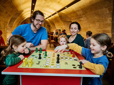 Familie speelt bordspel in historische kamer met gewelfde stenen muren in het fort Königstein.