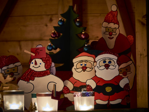 Weihnachtsmarkt Weihnachtliche Holzfiguren, darunter Schneemänner und Weihnachtsmänner, umgeben von Kerzenlicht.