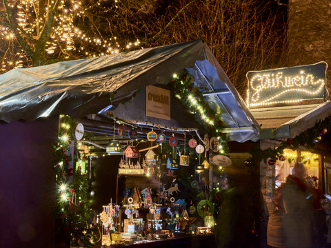Weihnachtsmarkt Weihnachtsmarktstand bei Nacht mit leuchtender Dekoration, handgefertigten Holzartikeln und Lichtern.