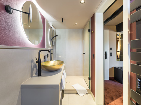 Hotel von Landsberg Modernes Badezimmer mit goldener Waschschale, großer Dusche, LED-beleuchtetem Spiegel und stilvoller Einrichtung.