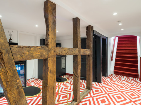 Hotel von Landsberg Barrierefreier, moderner Innenraum mit roten, geometrisch gemusterten Böden und sichtbaren Holzbalken.