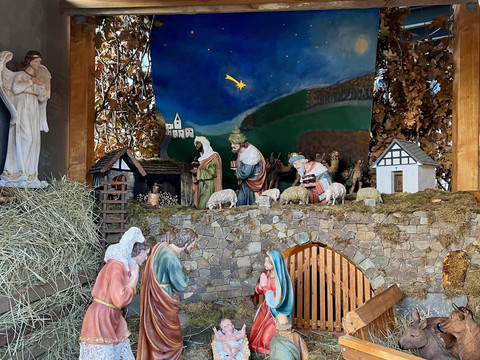 Krippe Museum außen Liebevoll gestaltete Weihnachtskrippe mit Figuren der Heiligen Familie und Hirten unter einem Sternenhimmel.