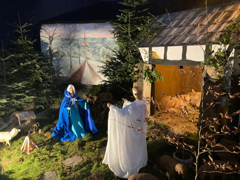 Verkündigungsszene St. Martinus Weihnachtliche Krippenszene mit Maria und Josef im Stall neben einem schlafenden Esel, umgeben von Tannen.