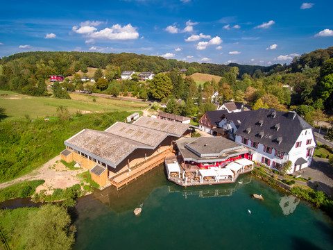 Herrenstrunden 4.png Luftaufnahme zeigt malerische Landschaft in Bergisch Gladbach mit traditionellen Gebäuden und Teich.