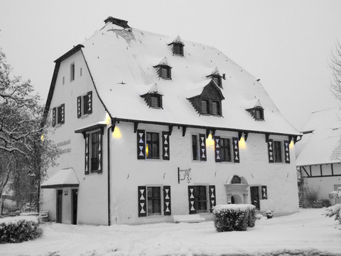 Malteser Komturei-Winter-2 Ein verschneites Fachwerkhaus mit leuchtenden Fenstern im winterlichen Bergisch Gladbach.