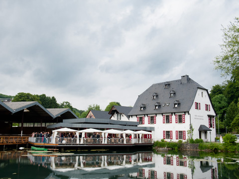 Malteser Komturei- 2 Historische Mühle in Bergisch Gladbach, Deutschland, bei wolkigem Himmel und ruhigem Wasser.