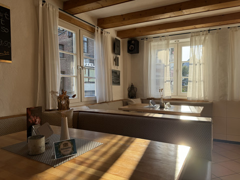 Dürscheider Hof - Innenansicht Rustikales Café mit Holzbalkendecke, sonnenbeschienenen Holztischen und gemütlichen Sitzbänken.