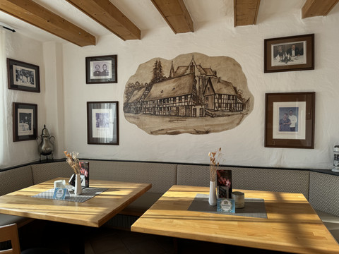 Dürscheider Hof - Innenansicht Gemütliche Sitzecke in einem Restaurant mit historischen Fotos und einer Zeichnung eines Fachwerkhauses.